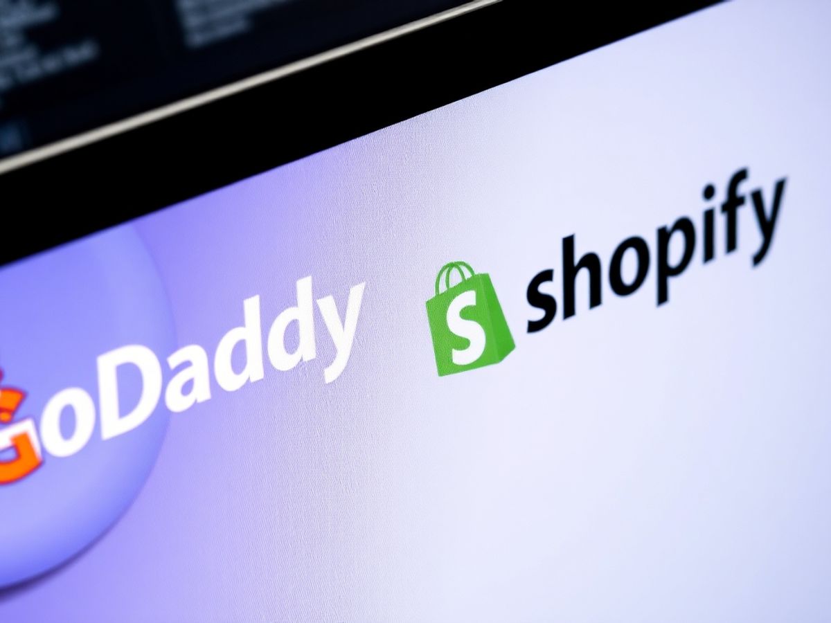 Computer screen with GoDaddy and Shopify logos.